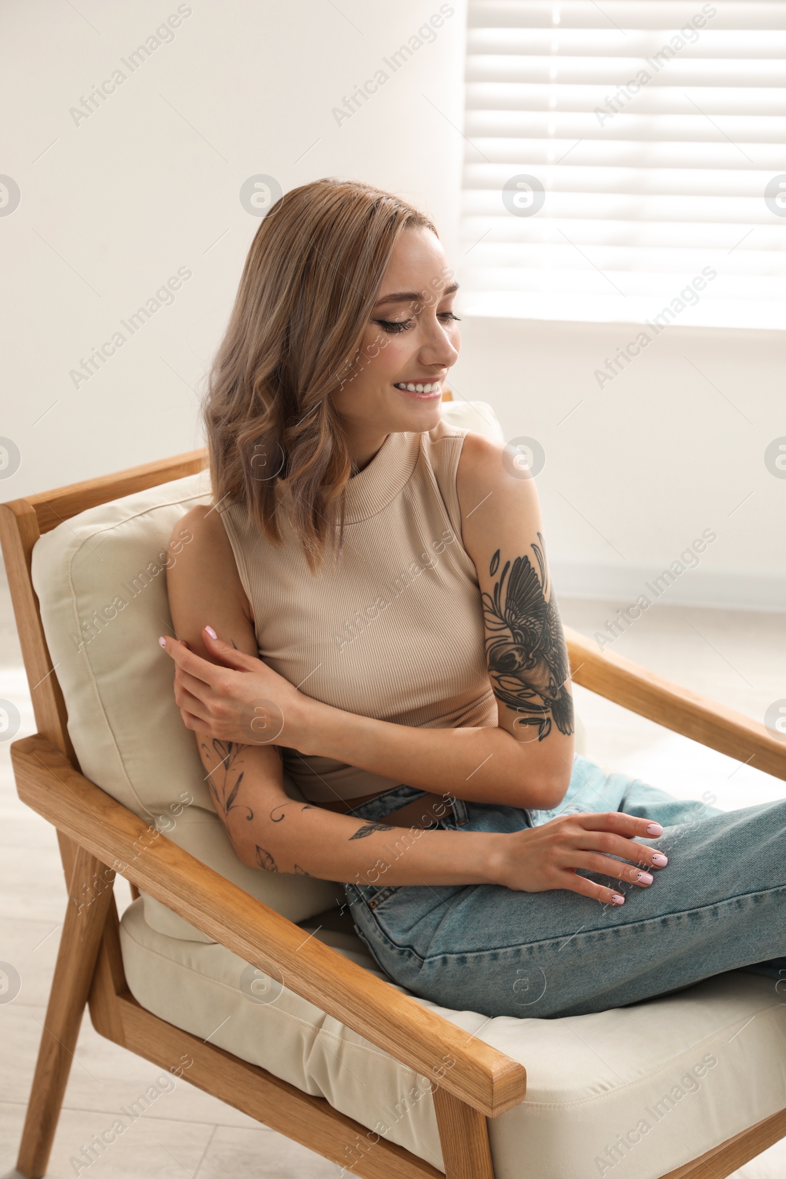 Photo of Beautiful woman with tattoos on arms resting at home