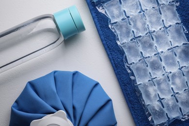 Bottle of water, ice pack, cold compress and towel on white background, flat lay. Heat stroke treatment