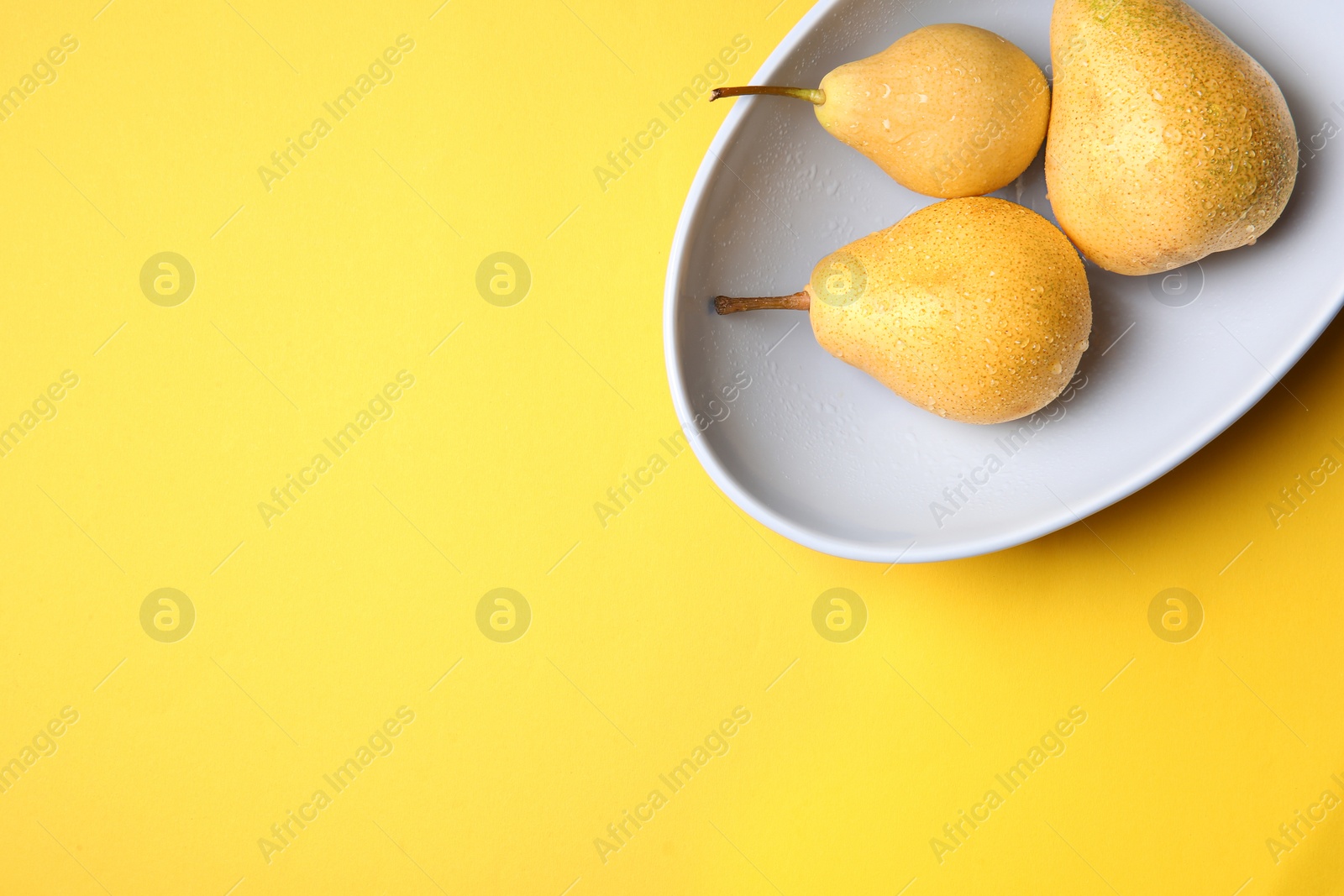 Photo of Plate with ripe pears on color background, top view. Space for text