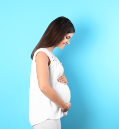 Photo of Happy pregnant woman posing on color background. Space for text