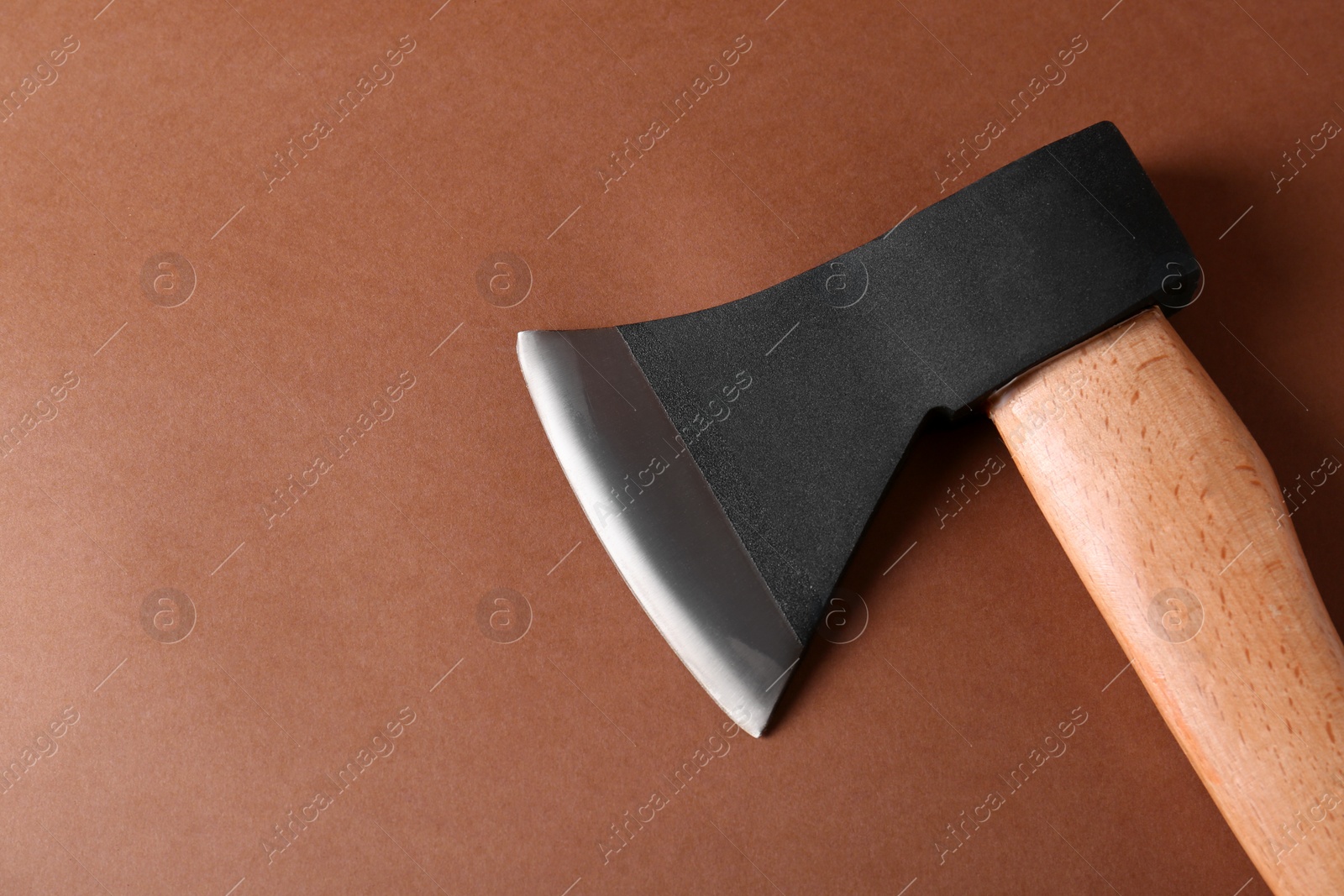 Photo of Ax with wooden handle on brown background, above view. Space for text