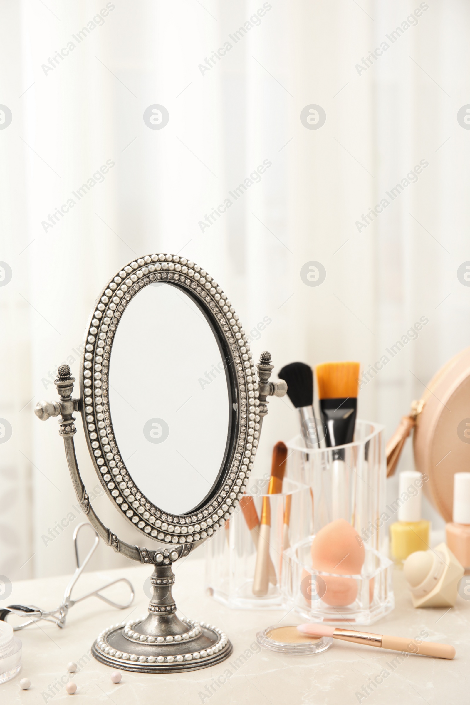 Photo of Mirror in antique frame and different cosmetics on dressing table. Beauty blogger