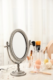 Mirror in antique frame and different cosmetics on dressing table. Beauty blogger