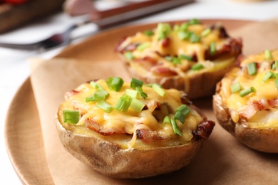 Photo of Plate of baked potatoes with cheese and bacon on table, closeup