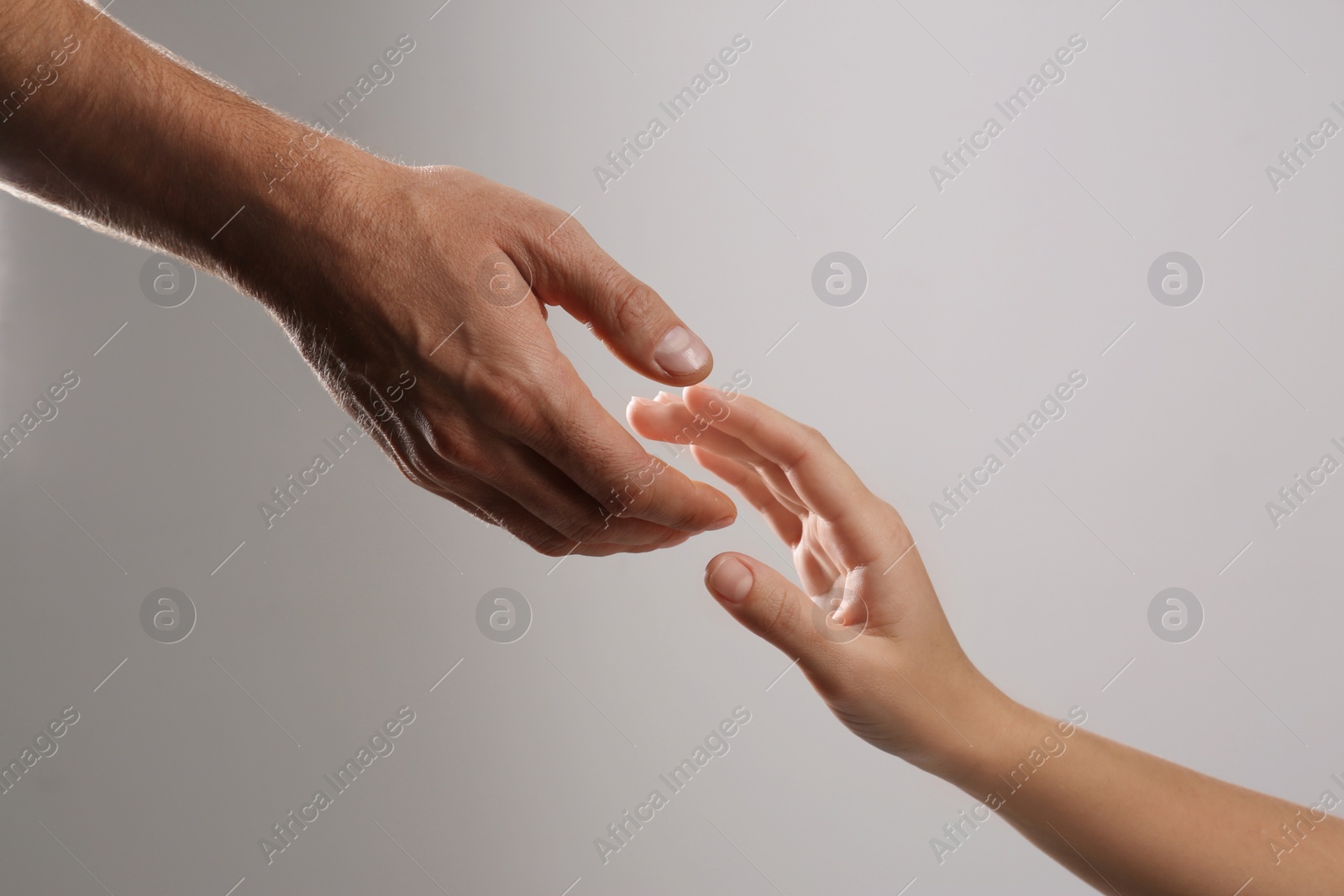 Photo of Man reaching for woman's hand on grey background, closeup. Help and support concept