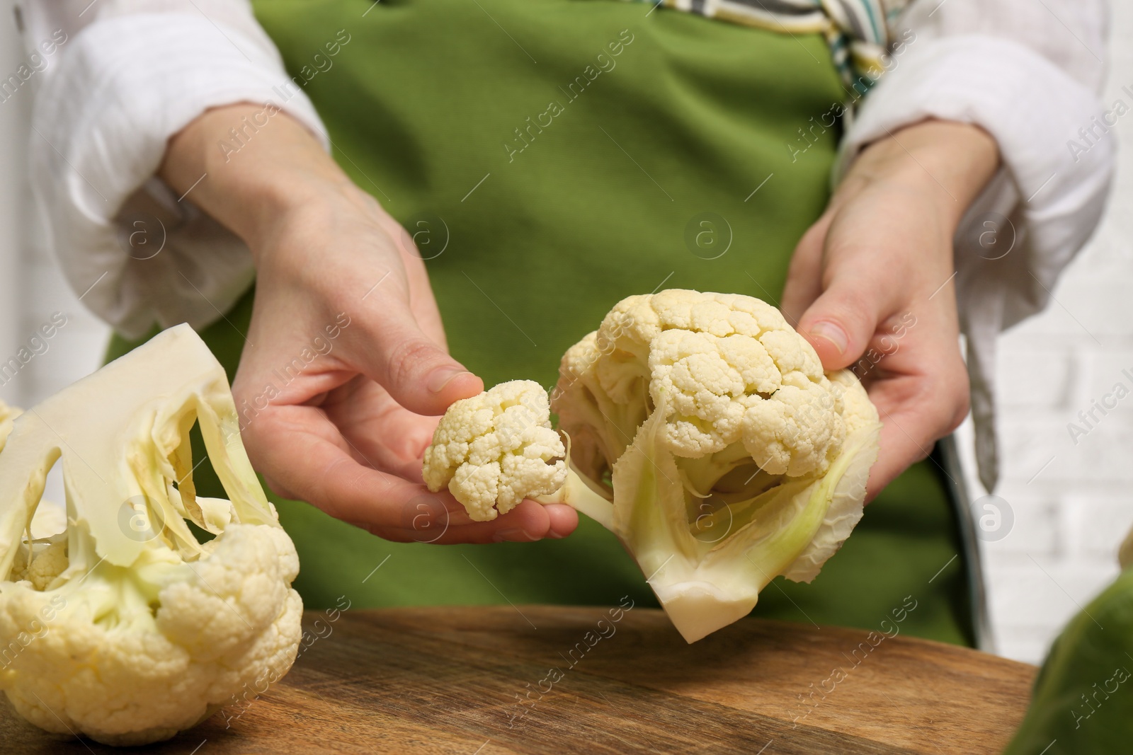 Photo of Woman holding fresh cauliflower above wooden board, closeup