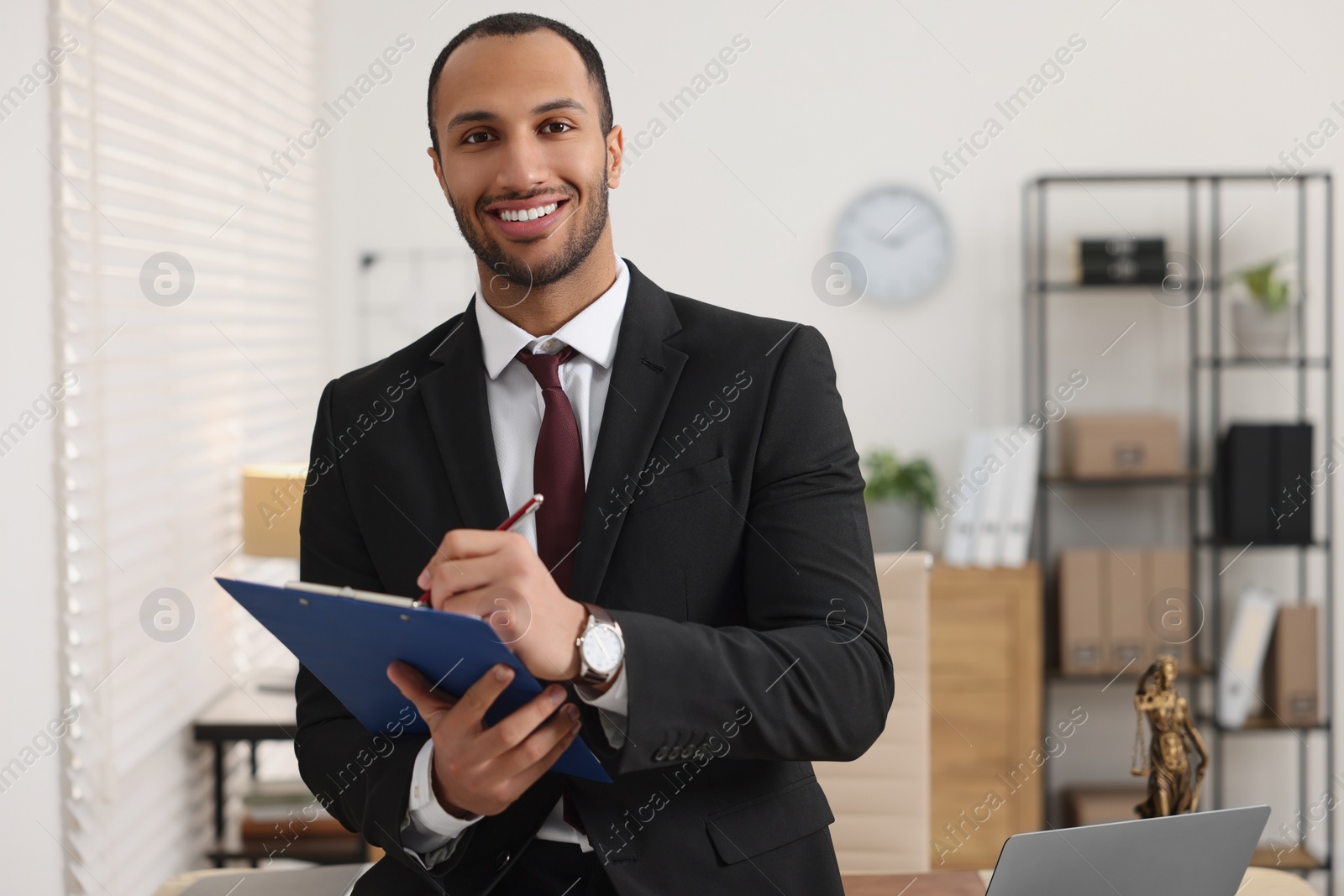 Photo of Smiling young man with clipboard writing notes in office. Lawyer, businessman, accountant or manager