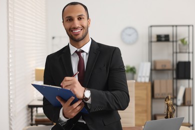 Smiling young man with clipboard writing notes in office. Lawyer, businessman, accountant or manager