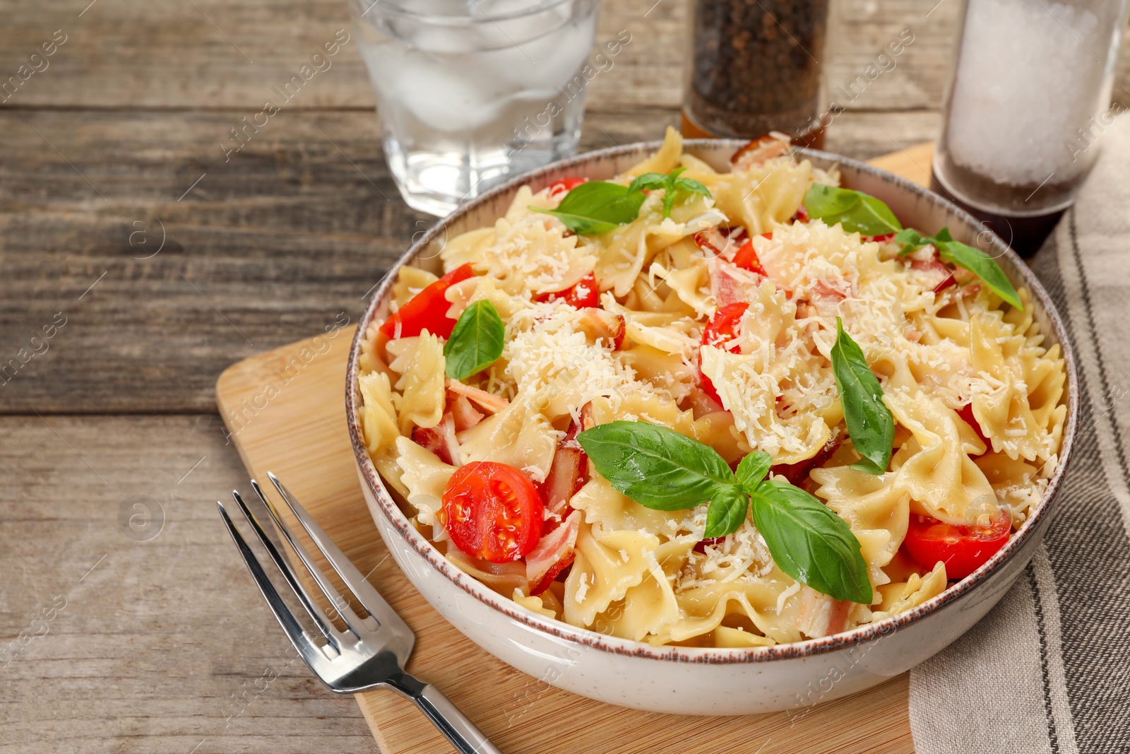 Photo of Delicious pasta with tomatoes, basil and parmesan cheese served on wooden table