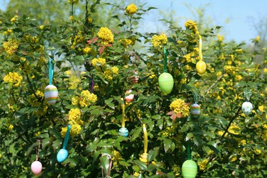 Photo of Beautifully painted Easter eggs hanging on tree outdoors