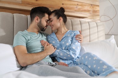 Photo of Happy couple in pajamas on bed at home