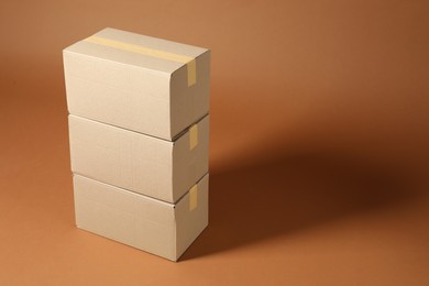 Stack of cardboard boxes on brown background, space for text