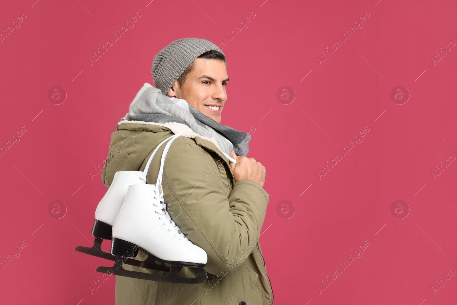 Photo of Happy man with ice skates on pink background