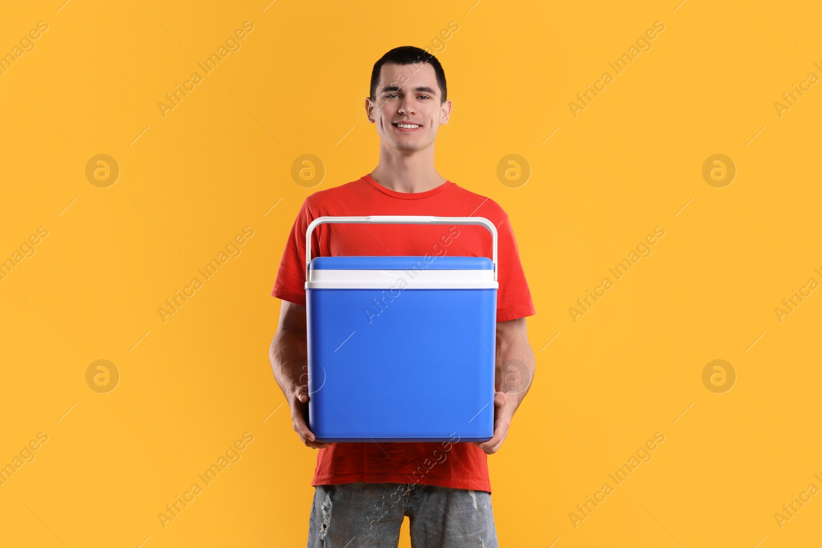 Photo of Man with blue cool box on orange background