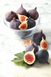 Photo of Whole and cut tasty fresh figs on white marble table