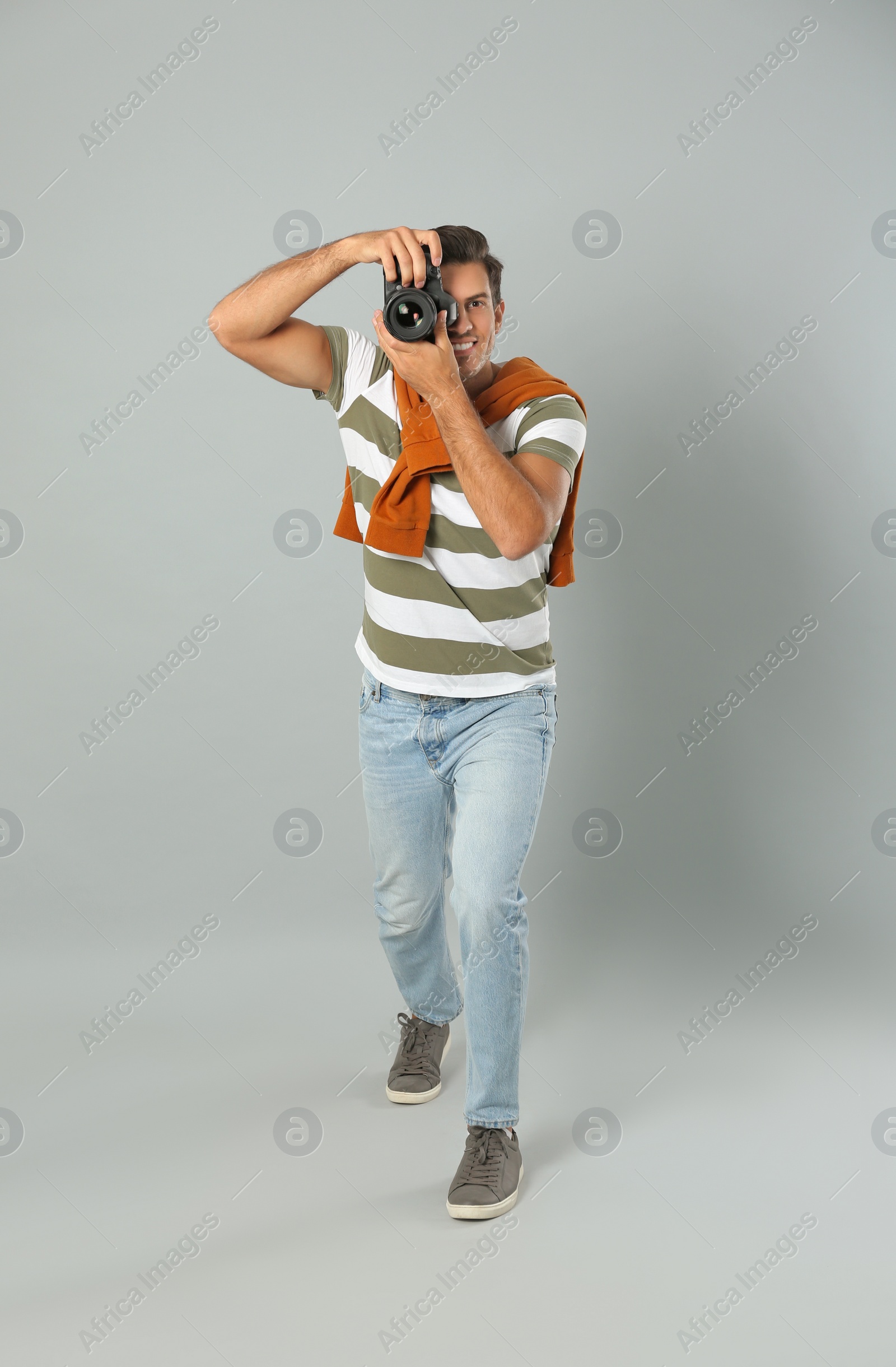 Photo of Professional photographer working on light grey background in studio