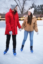Happy young couple skating at outdoor ice rink
