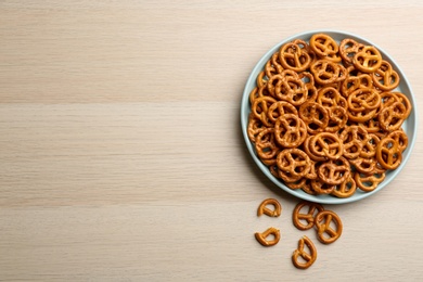 Photo of Delicious pretzel crackers on wooden table, flat lay. Space for text