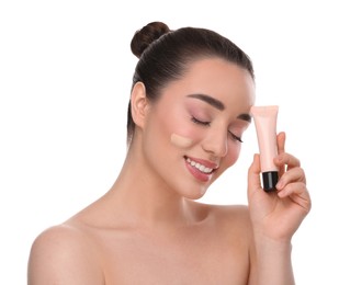 Woman holding tube of foundation on white background