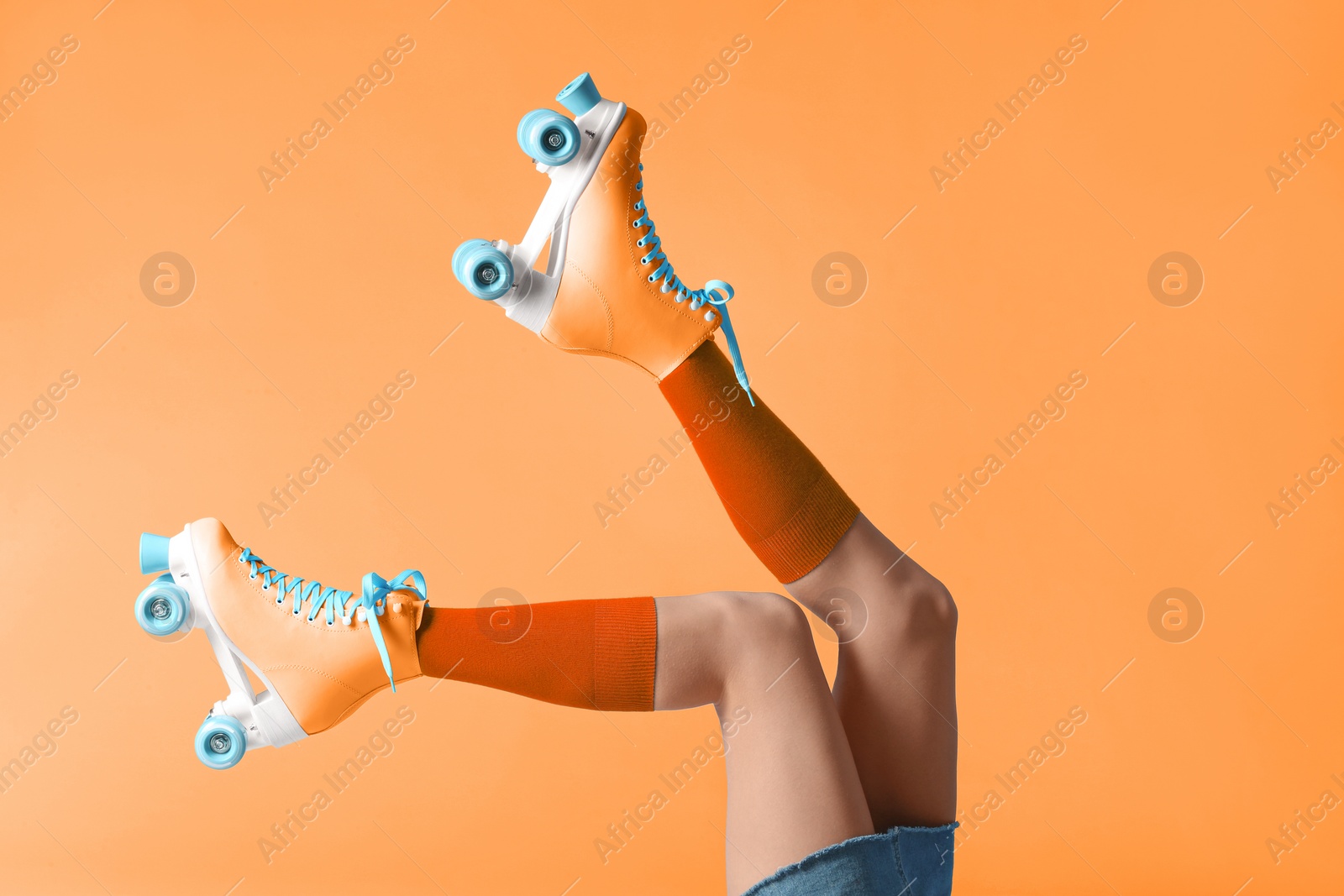 Image of Woman with vintage roller skates on orange background, closeup