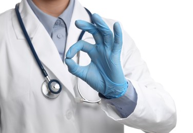 Doctor wearing light blue medical gloves showing ok gesture on white background, closeup