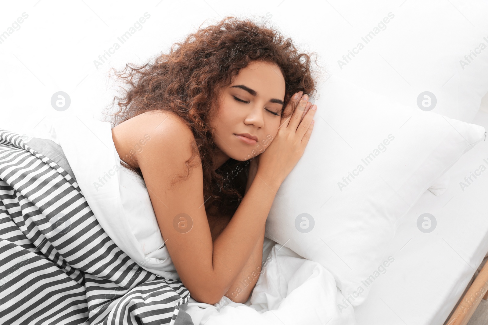 Photo of Young African-American woman sleeping on soft pillow at home. Bedtime