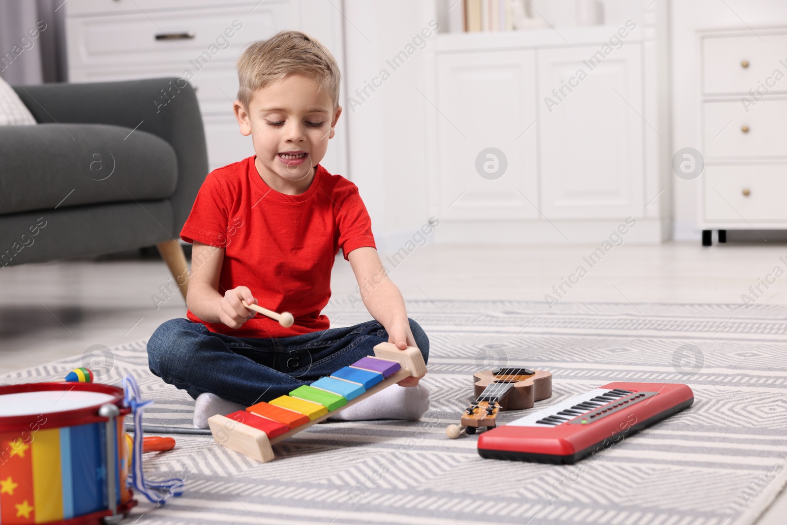 Photo of Little boy playing toy xylophone at home