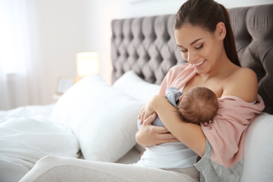 Young woman breastfeeding her baby in bedroom