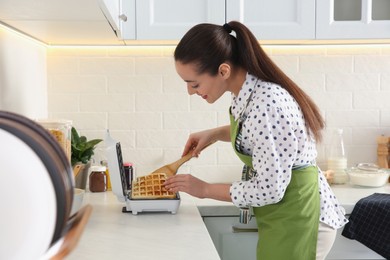 Photo of Woman making delicious Belgian waffles in kitchen