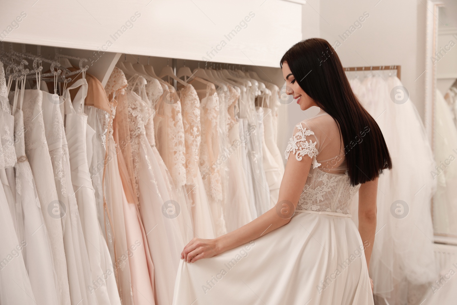 Photo of Woman trying on beautiful wedding dress in boutique