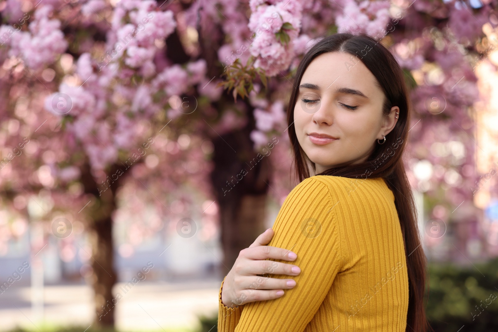 Photo of Beautiful woman near blossoming tree on spring day, space for text