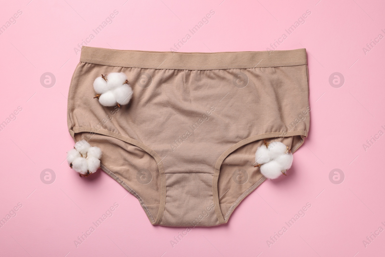 Photo of Beige women's underwear and cotton flowers on pink background, flat lay