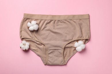 Beige women's underwear and cotton flowers on pink background, flat lay