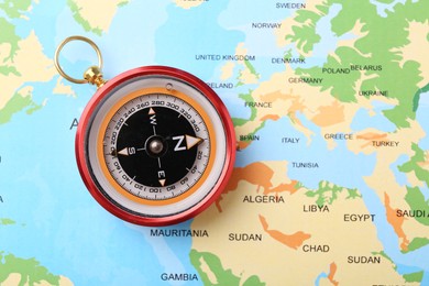 Photo of Compass on world map, top view. Navigation equipment