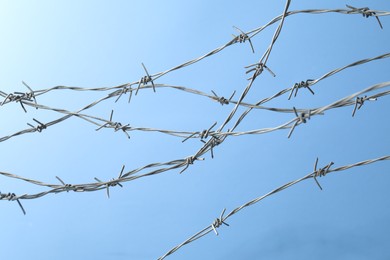 Photo of Metal barbed wire on light blue background