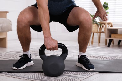 Muscular man training with kettlebell at home, closeup