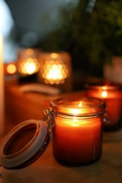 Lit candles on wooden table in dark room. Space for text