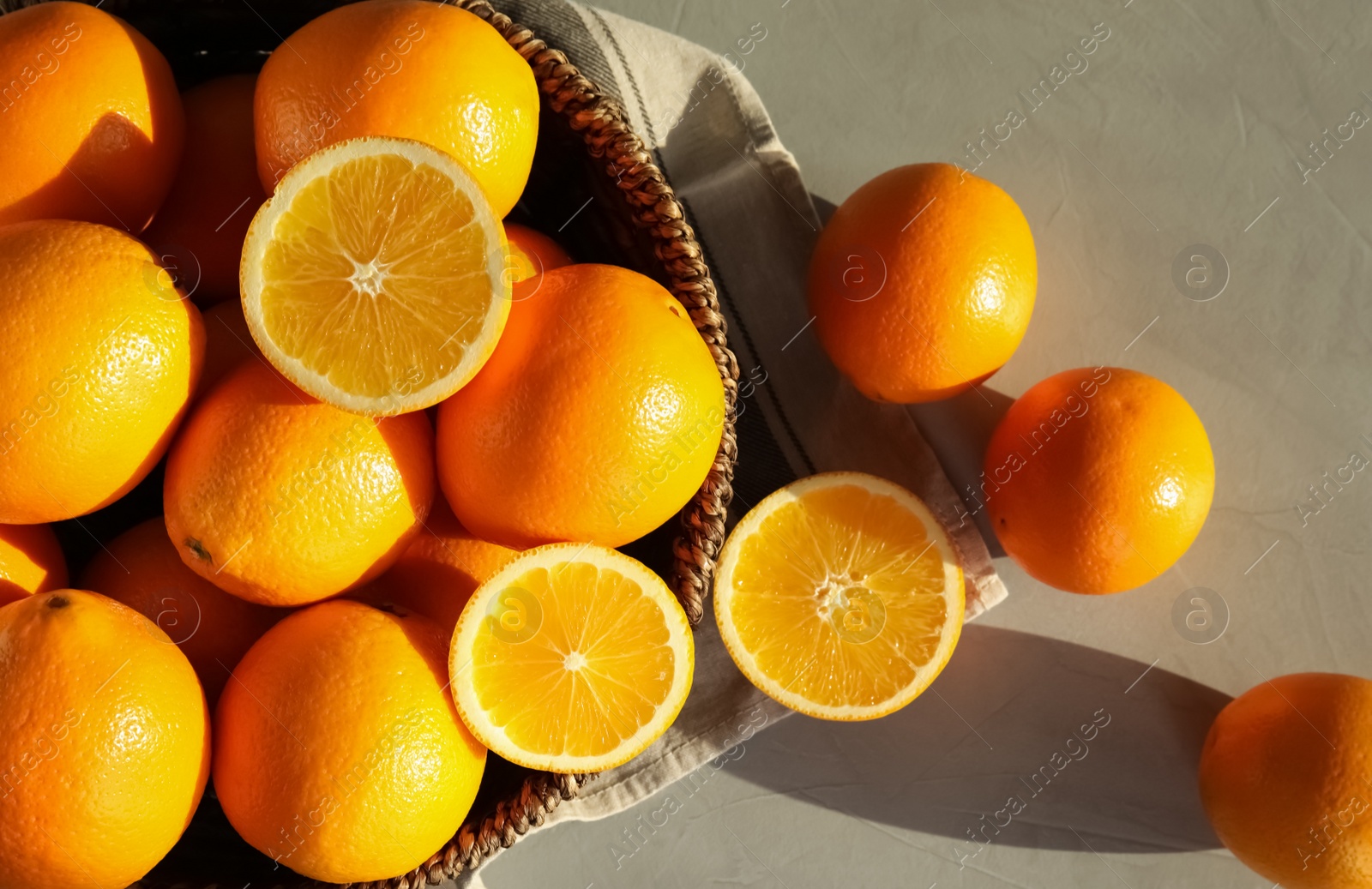 Photo of Fresh juicy oranges in wicker basket on table, top view