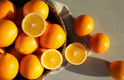 Photo of Fresh juicy oranges in wicker basket on table, top view