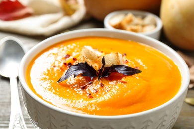 Delicious pumpkin soup in bowl on table, closeup