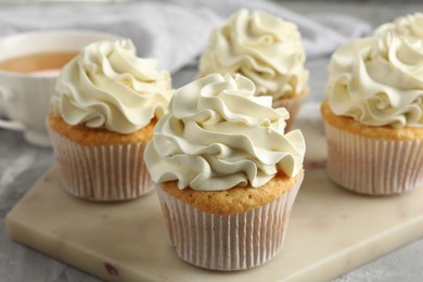 Photo of Tasty cupcakes with vanilla cream on grey table, closeup