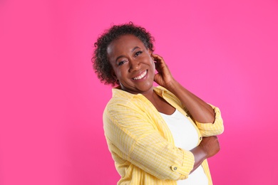 Portrait of happy African-American woman on pink background