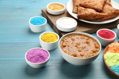 Traditional Indian food and color powders on light blue wooden table. Holi festival celebration