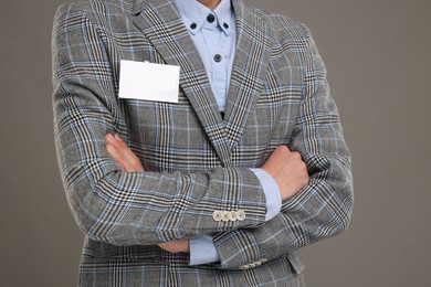 Man with blank badge on grey background, closeup