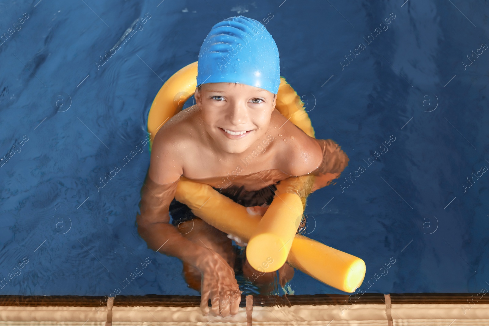 Photo of Little boy with swimming noodle in indoor pool