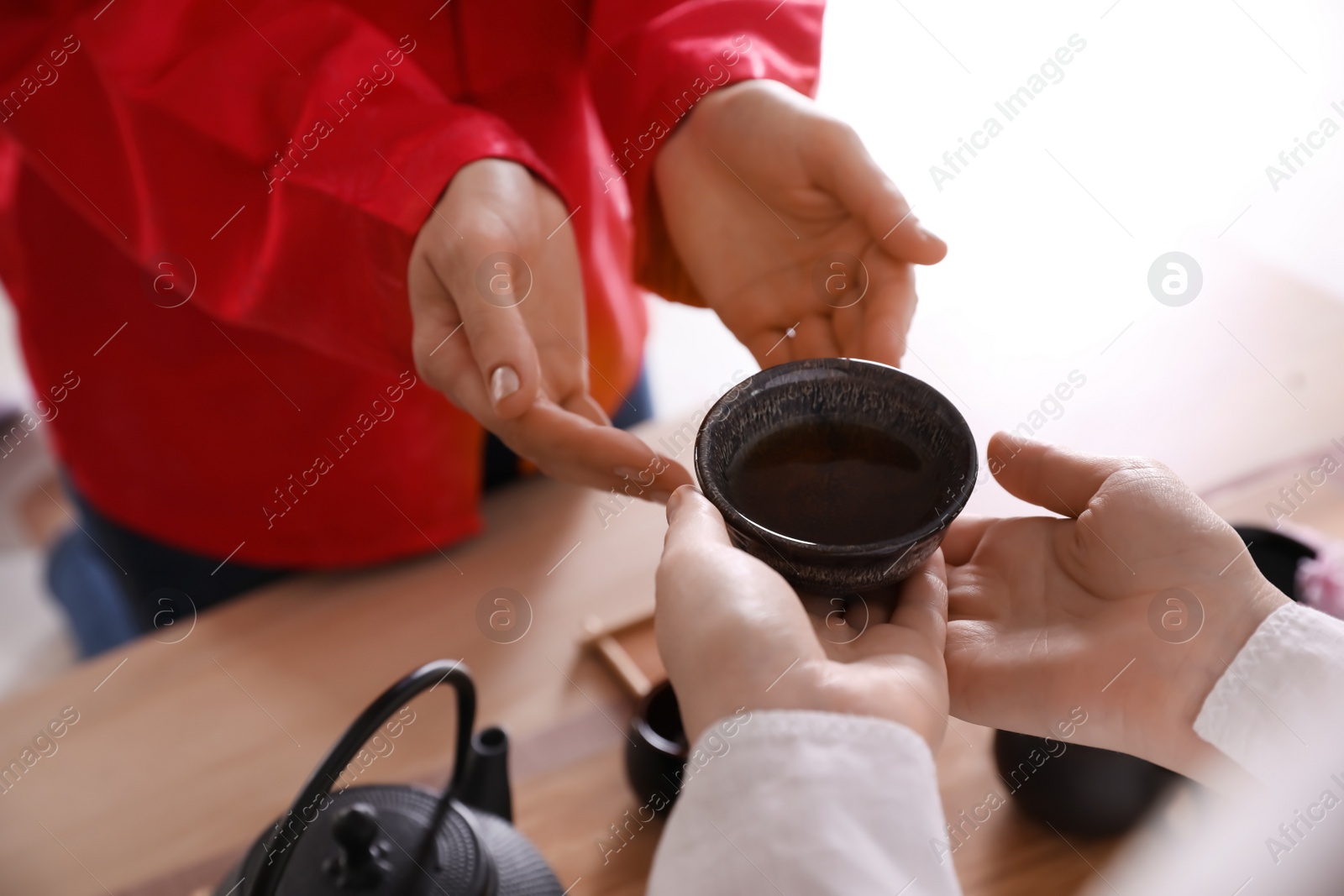 Photo of Master giving freshly brewed tea to guest during ceremony at table, closeup