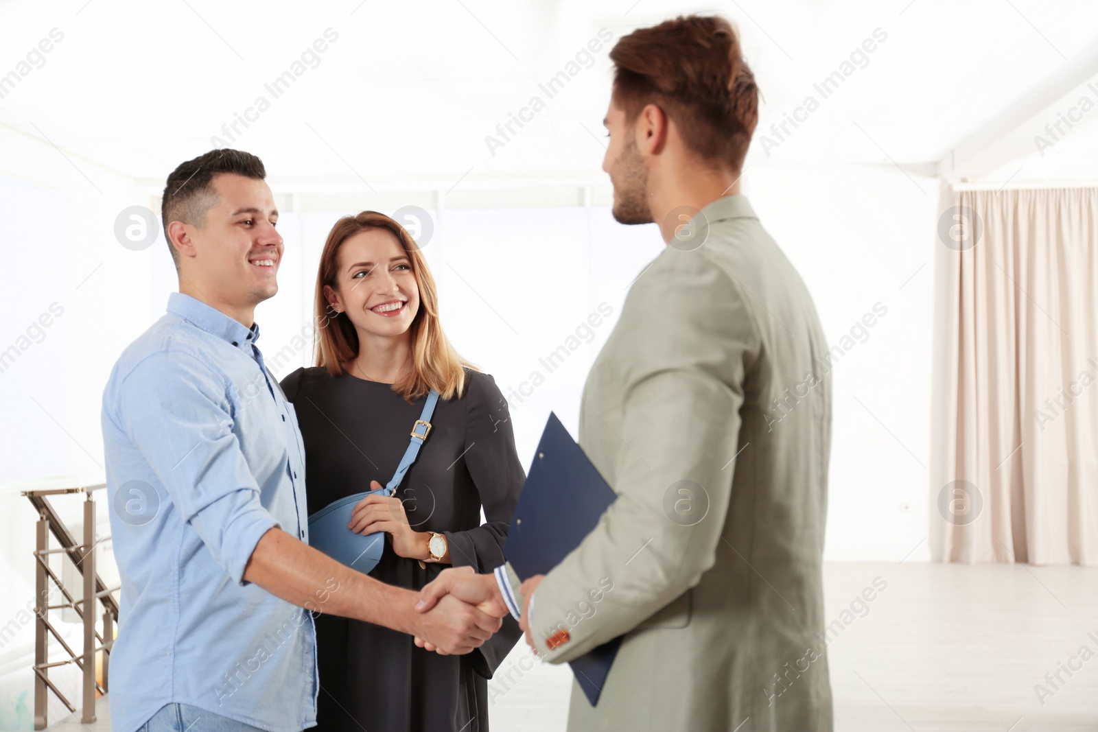 Photo of Real estate agent with young couple in new apartment