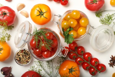 Pickling jars with fresh tomatoes on white table, flat lay