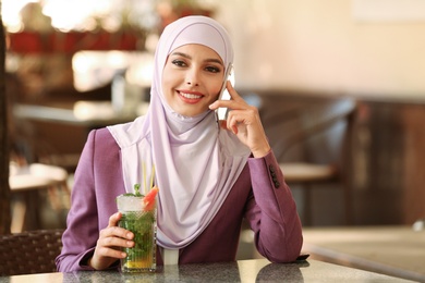 Muslim woman talking on phone in outdoor cafe