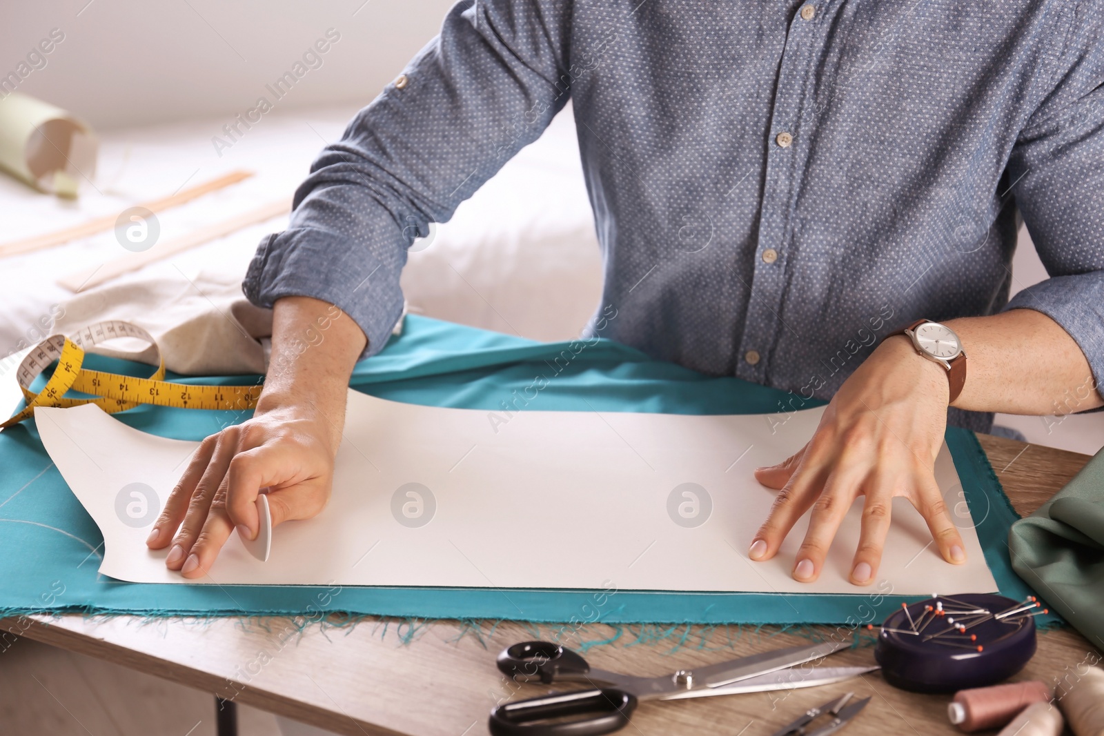 Photo of Tailor working with cloth at table in atelier